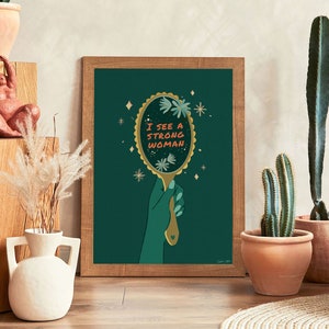 artwork of a quote "i see a strong woman" is written on a mirror held by a woman hand, this artwork is in emerald green in color .it is a vertical poster