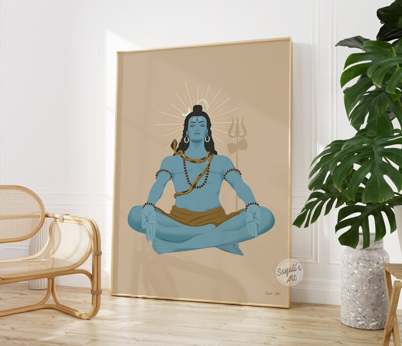 May include: A framed wall art print featuring a blue-skinned figure in a meditative lotus position. The figure has a snake draped around the neck, a crescent moon above the head, and a trident symbol in the background on a tan-colored field.