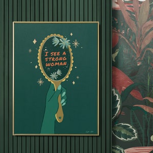 artwork of a quote "i see a strong woman" is written on a mirror held by a woman hand, this artwork is in emerald green in color .it is a vertical poster