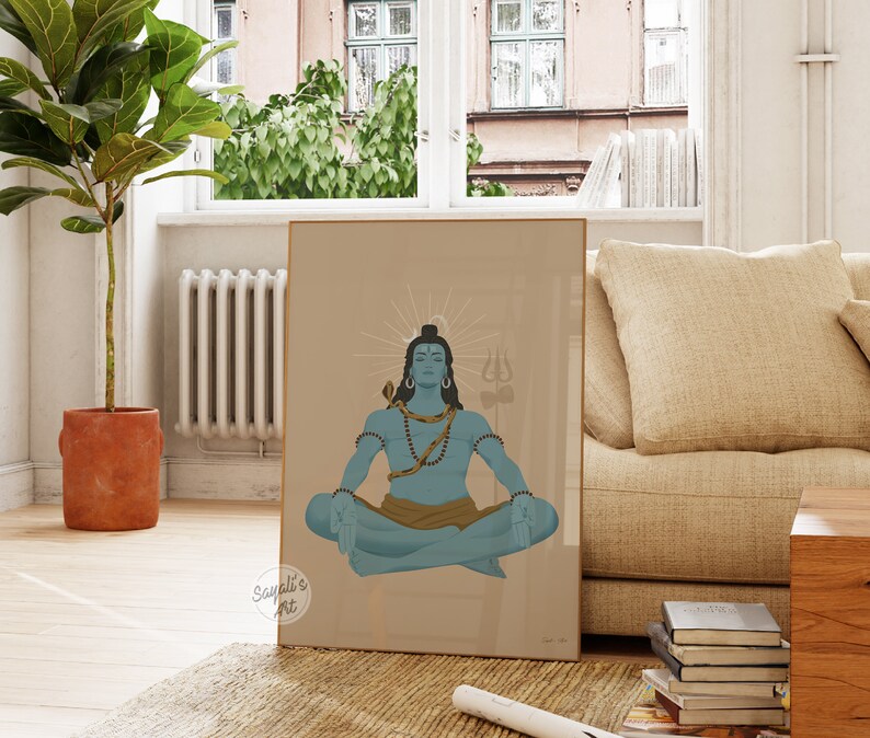May include: A framed wall art print featuring a blue-skinned deity sitting in a meditative lotus position. The figure has a snake coiled around the neck, wears beads, and is positioned before a sunburst halo with a trident symbol in the background.
