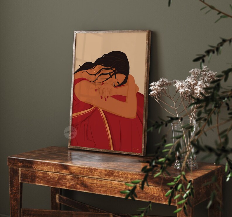 Puede incluir: Una ilustraci&oacute;n digital de una mujer con el pelo largo y oscuro que lleva un sari rojo con ribetes dorados. Est&aacute; sentada con los brazos enroscados alrededor de s&iacute; misma, mirando hacia abajo.