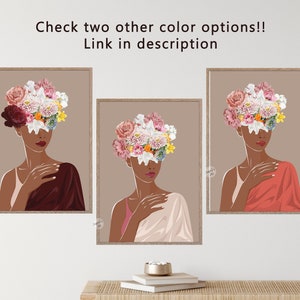 May include: Three framed illustrations of a woman with a floral crown covering her face. The woman in the left frame is wearing a burgundy dress, the woman in the centre frame is wearing a light pink dress, and the woman in the right frame is wearing a coral dress. The background of each frame is a light brown colour.