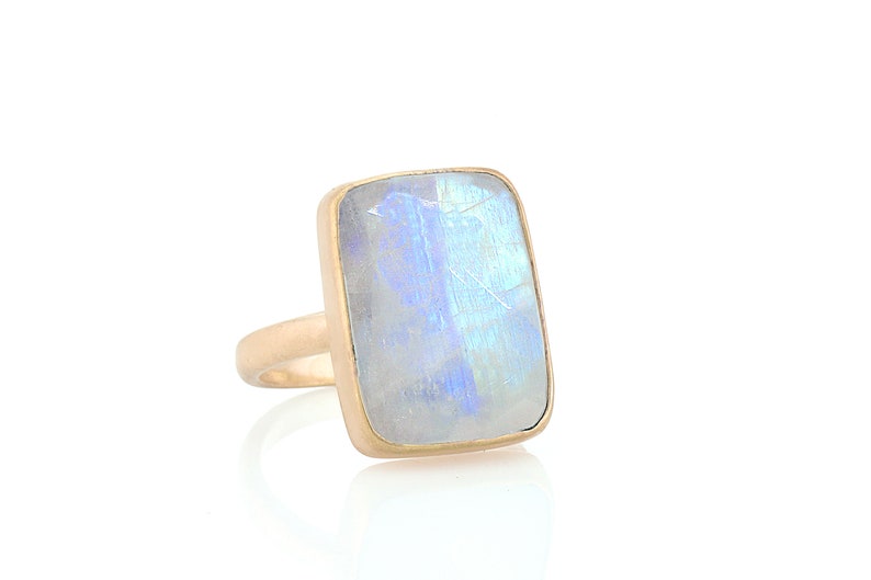 May include: A gold ring with a large, rectangular, iridescent moonstone.