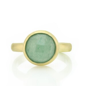 May include: A gold ring with a round green gemstone set in a bezel setting.