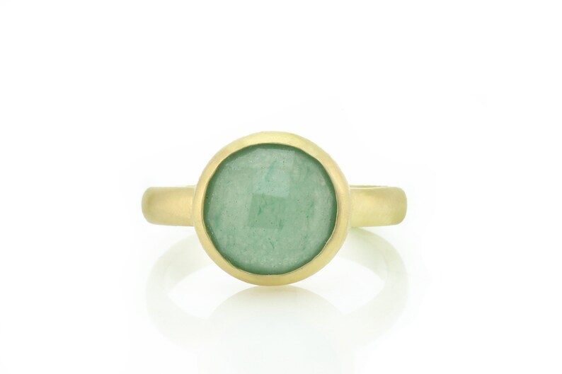 May include: A gold ring with a round green gemstone set in a bezel setting.