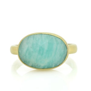Puede incluir: Un anillo de oro con una gran piedra preciosa verde de forma ovalada.