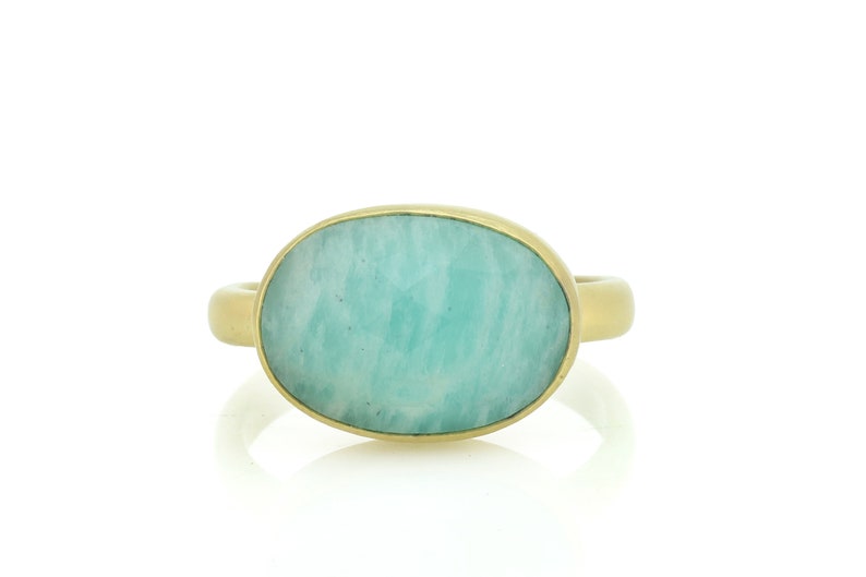 Puede incluir: Un anillo de oro con una gran piedra preciosa verde de forma ovalada.