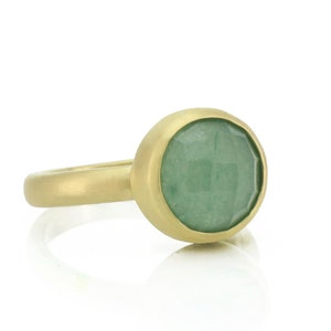 May include: A gold ring with a green gemstone set in a bezel setting.