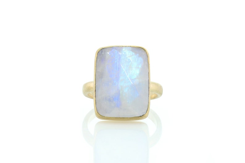 May include: A gold ring with a large, rectangular, iridescent moonstone.