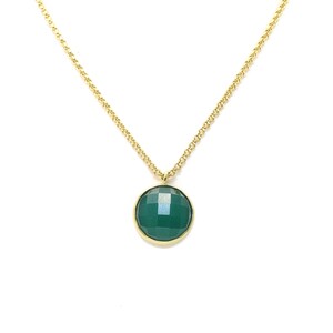 Op de afbeelding: Een gouden ketting met een hanger van een groene edelsteen.