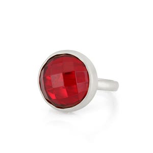 May include: A silver ring with a large, red, faceted gemstone.