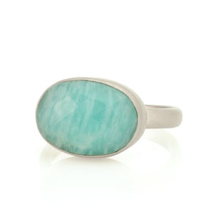 Puede incluir: Un anillo de plata con una gran piedra ovalada de color azul claro.