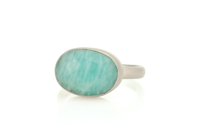 Puede incluir: Un anillo de plata con una gran piedra ovalada de color azul claro.