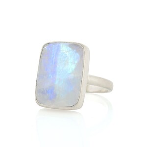May include: A silver ring with a large, rectangular, iridescent moonstone.