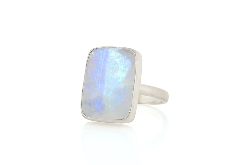 May include: A silver ring with a large, rectangular, iridescent moonstone.