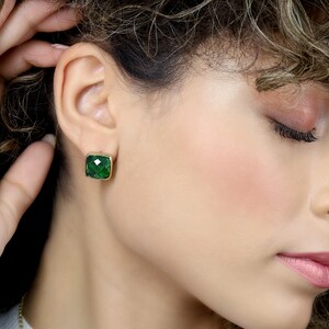 May include: A pair of gold earrings with square green gemstones.