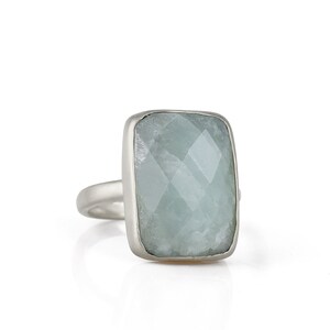 May include: A silver ring with a large, rectangular, light blue aquamarine gemstone.