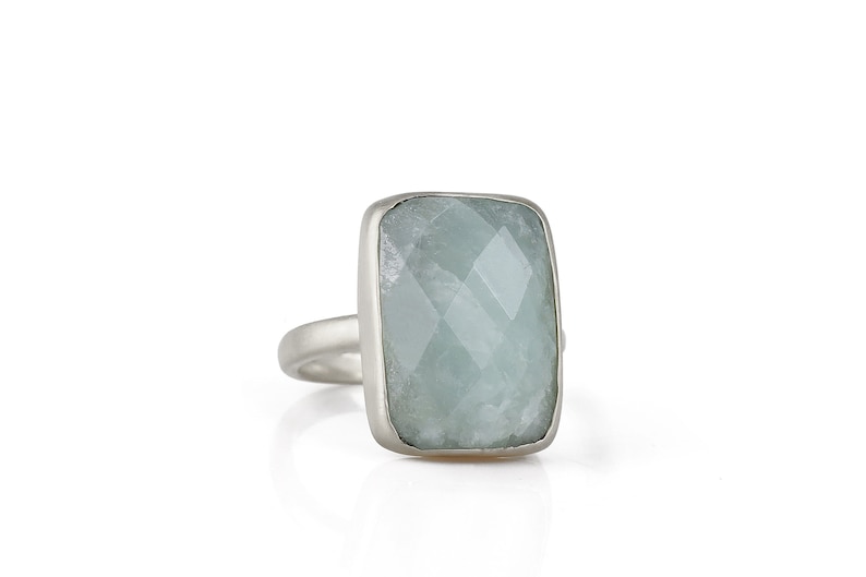 May include: A silver ring with a large, rectangular, light blue aquamarine gemstone.