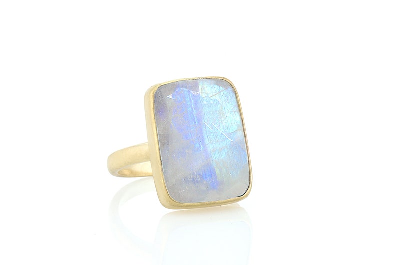 May include: A gold ring with a large, rectangular, iridescent moonstone.