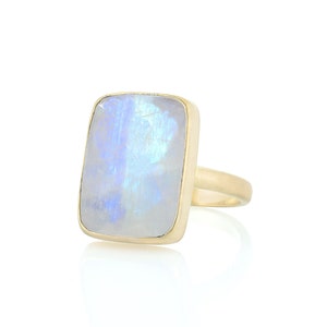 May include: A gold ring with a large, rectangular, iridescent moonstone.