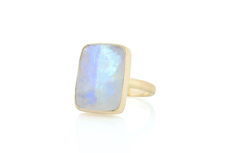 May include: A gold ring with a large, rectangular, iridescent moonstone.