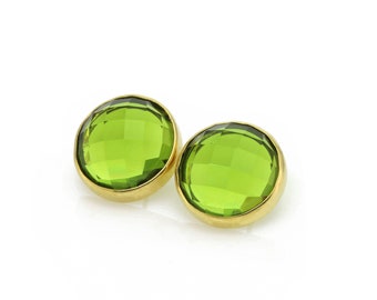 May include: A pair of gold earrings with green gemstone accents. The gemstones are round and have a faceted design.