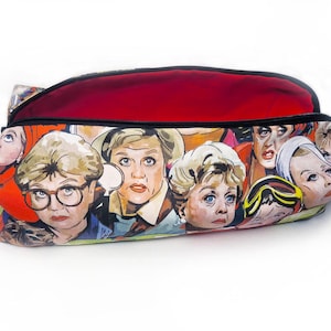 May include: A red and black zippered pouch with a colourful print of cartoon faces. The pouch is open and the inside lining is red.
