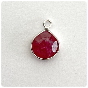May include: A silver pendant with a teardrop-shaped red gemstone.