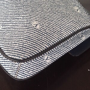 May include: A blue and white striped fabric handbag with a black leather trim. The fabric has a repeating pattern of small circles.