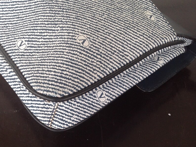 May include: A blue and white striped fabric handbag with a black leather trim. The fabric has a repeating pattern of small circles.