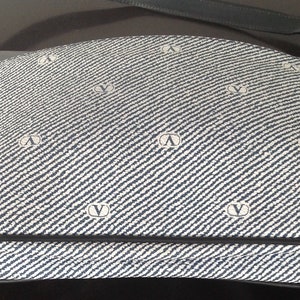 May include: A blue and white patterned shoulder bag with a black leather strap. The bag has a repeating logo pattern.