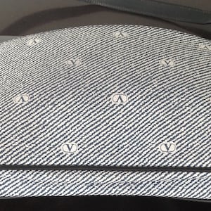 May include: A blue and white patterned shoulder bag with a black leather strap. The bag has a repeating logo pattern.
