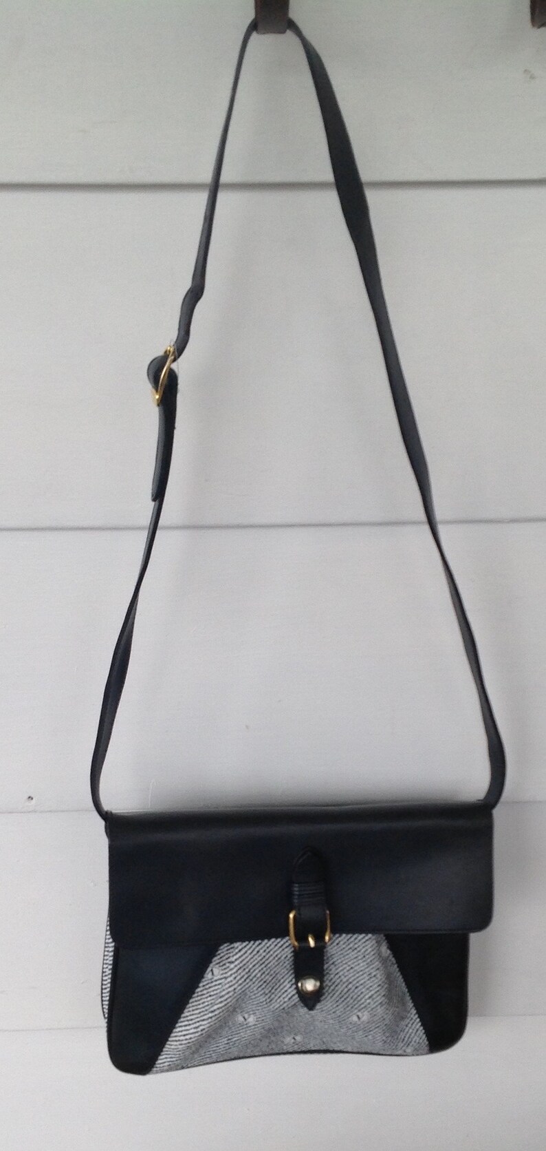 May include: A black leather shoulder bag with a silver buckle and a white and black patterned flap.