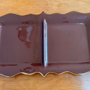 May include: A brown ceramic serving tray with a gold trim. The tray is divided into two sections.