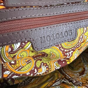 K&ouml;nnte beinhalten: Nahaufnahme des Innenraums einer braunen Lederhandtasche. Die Tasche hat ein Paisley-Musterfutter in Gelb-, Orange- und Braunt&ouml;nen. Der Markenname "Lookheart" ist auf einem Lederetikett eingepr&auml;gt. Die Modellnummer "MO10105" ist ebenfalls sichtbar.