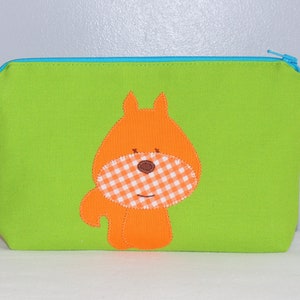 May include: A lime green zippered pouch with a cartoon squirrel applique. The squirrel is orange with a checkered pattern on its face and chest. The zipper is turquoise, and a small tag with the word "Touch" is attached.
