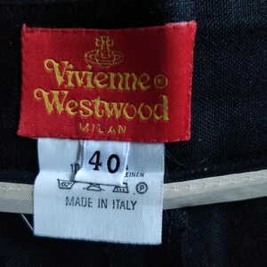 Puede incluir: Primer plano de una etiqueta roja de Vivienne Westwood con letras doradas, sobre una etiqueta blanca con el n&uacute;mero 40. La etiqueta dice "Vivienne Westwood MILAN" y "MADE IN ITALY".