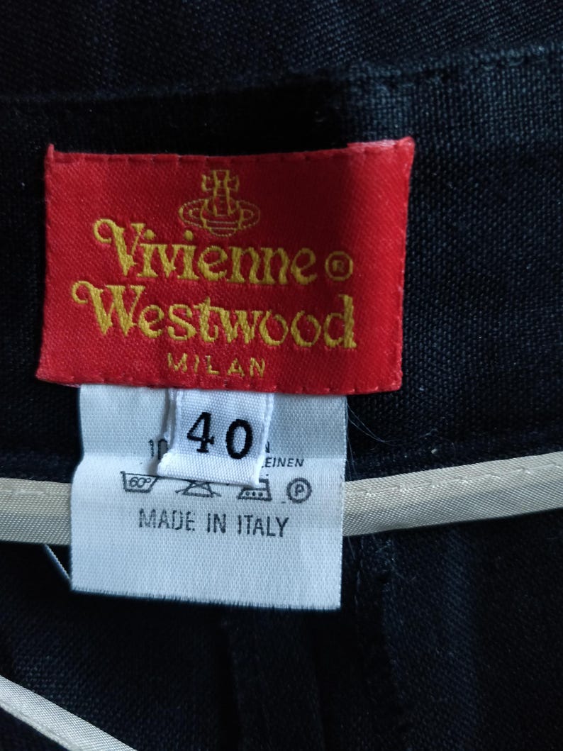 Puede incluir: Primer plano de una etiqueta roja de Vivienne Westwood con letras doradas, sobre una etiqueta blanca con el n&uacute;mero 40. La etiqueta dice "Vivienne Westwood MILAN" y "MADE IN ITALY".