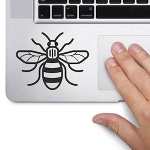 Könnte beinhalten: Ein schwarz-weißer Bienensticker auf einem silbernen Laptop.