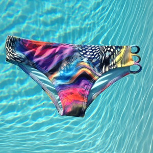 May include: A colorful swimsuit bottom with a bright abstract pattern, floating in a blue swimming pool.