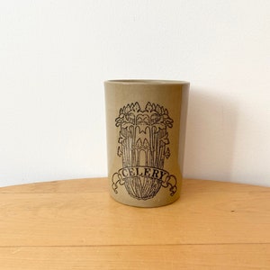 Może przedstawiać: Beżowy ceramiczny słoik z czarno-białym rysunkiem selera i napisem "CELERY" na banerze.