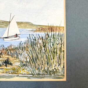 Puede incluir: Pintura acuarela de un velero en un lago con altas ca&ntilde;as verdes en primer plano. El cielo es azul claro y el agua es azul verdoso claro.