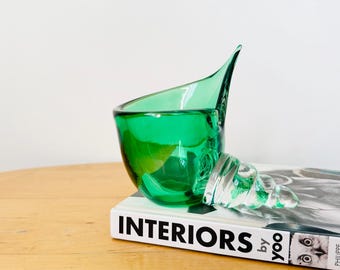 Może przedstawiać: Zielona szklana miska w kształcie muszli leży na książce zatytułowanej "Interiors by Yoo".