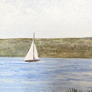 Puede incluir: Una pintura de acuarela de un velero en una masa de agua con una costa verde cubierta de hierba en el fondo. El cielo es de un azul claro con nubes blancas.