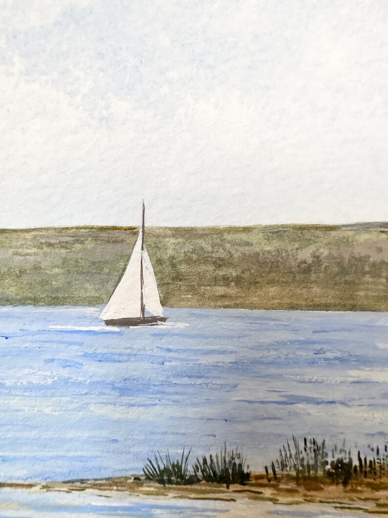 Puede incluir: Una pintura de acuarela de un velero en una masa de agua con una costa verde cubierta de hierba en el fondo. El cielo es de un azul claro con nubes blancas.