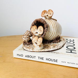 Könnte beinhalten: Keramikfigur von drei Mäusen, zwei schauen aus einem gestreiften Fass und eine sitzt auf dem Boden. Die Figur steht auf einem Buch mit dem Titel "Mad About The House" von Kate Watson-Smyth.