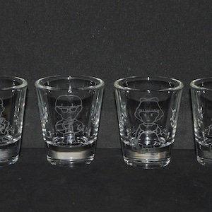 May include: Four clear glass shot glasses with etched cartoon characters. Each glass features a different character.