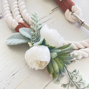 May include: White rope leash with a brown leather accent and a white floral accent with green succulents.