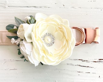 May include: A white faux flower with a rhinestone center is attached to a blush pink dog collar with a rose gold buckle.