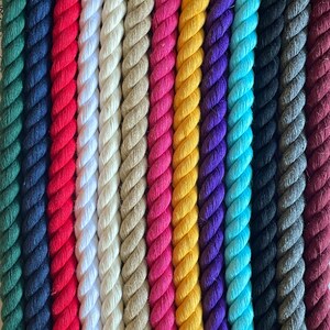 May include: A close-up of a variety of colourful twisted ropes. The ropes are arranged vertically, showcasing a spectrum of colours including red, white, tan, pink, yellow, purple, blue, black, grey, and burgundy. The texture of the rope is clearly visible.